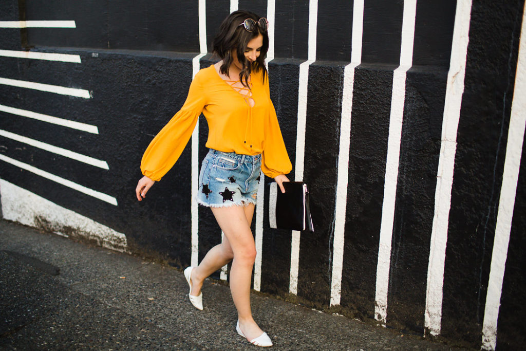 Star print denim distressed shorts and mustard lace up blouse